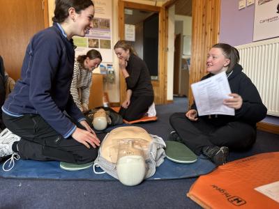 Four junior rangers practising CPR on a dummy