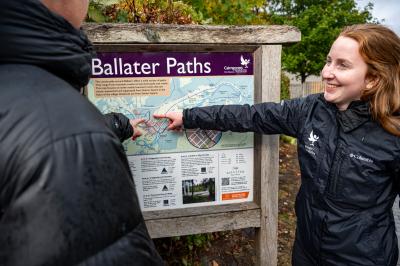 Ranger pointing out an area on a map sign to another person