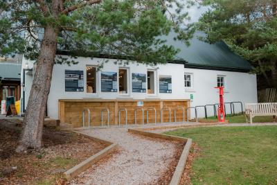 The outside of a white building with signage on the walls and bike parking