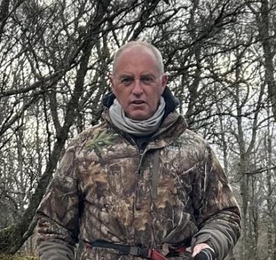 Person in camo jacket walking in woods