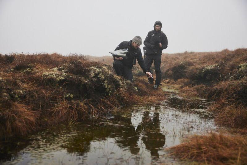 Image of Peatland ACTION Development Manager Matt Watson and Peatland ACTION Project Officer Simon Thomas taking notes around a peat bog on a misty day.