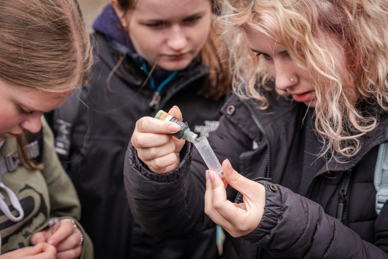 A group of students putting a solution in a tube while learning to monitor peatland in the National Park
