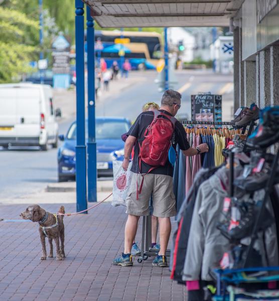 A shopper browses outdoor clothes rails with their dog on a lead in Aviemore.