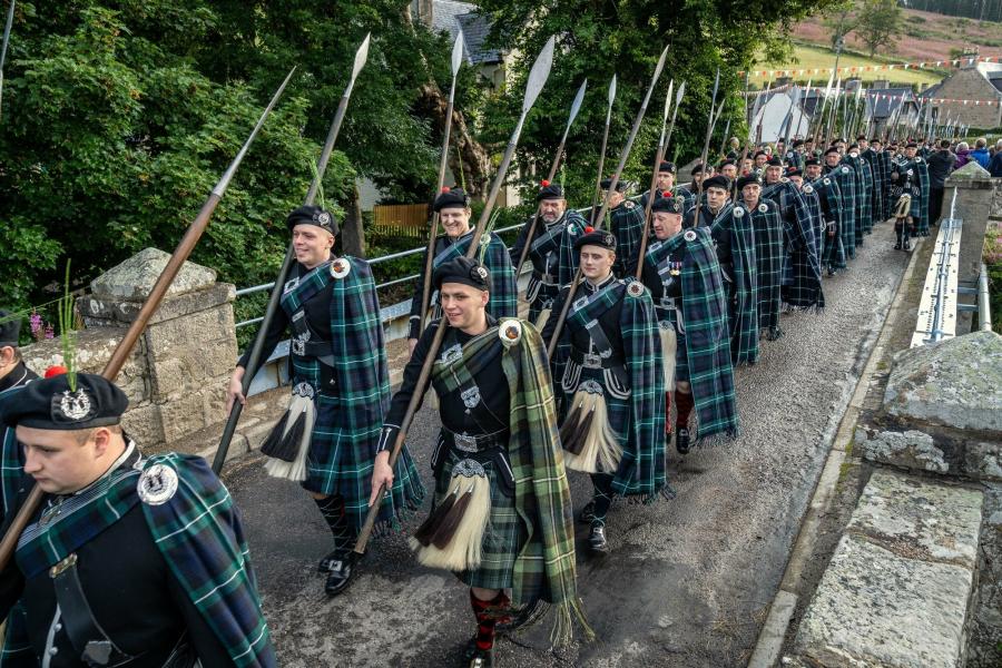 Men in traditional dress with spears take part in the March of the Lonach Highlanders.