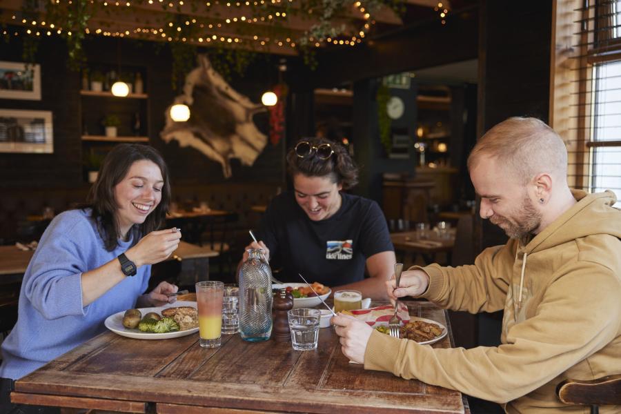 Three people enjoy a meal in a restaurant in the Cairngorms National Park.