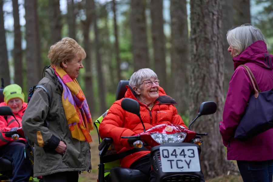 Four people in woodland, two on mobility scooters at Boat Of Garten health walk