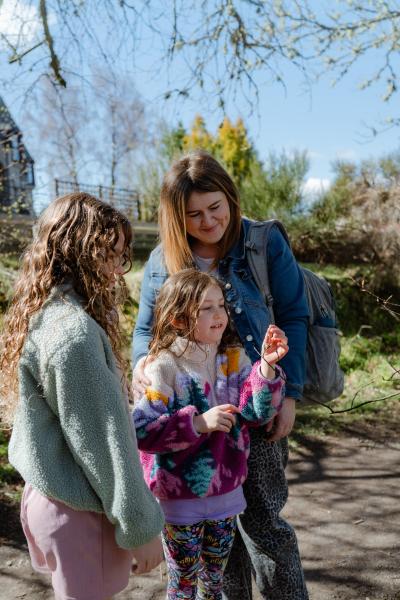 Family looking closely at new spring shoot on tree branch.