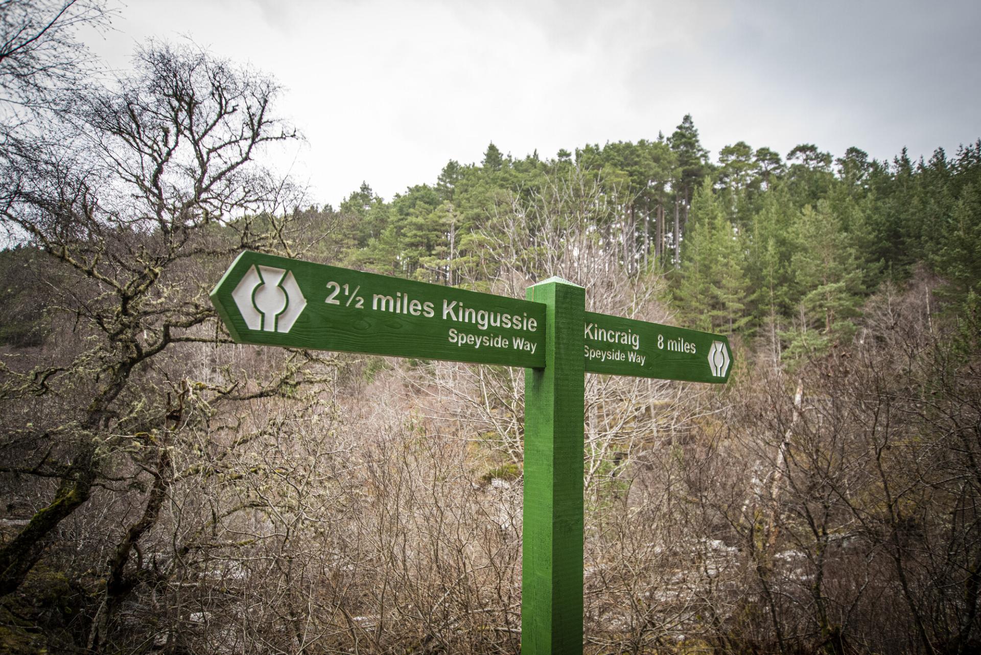 A green sign on the Speyside Way pointing to Kingussie and Kincraig