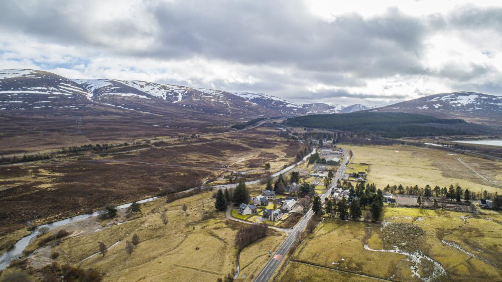 Aerial view of Dalwhinnie with surrounding mountains with patches of snow.