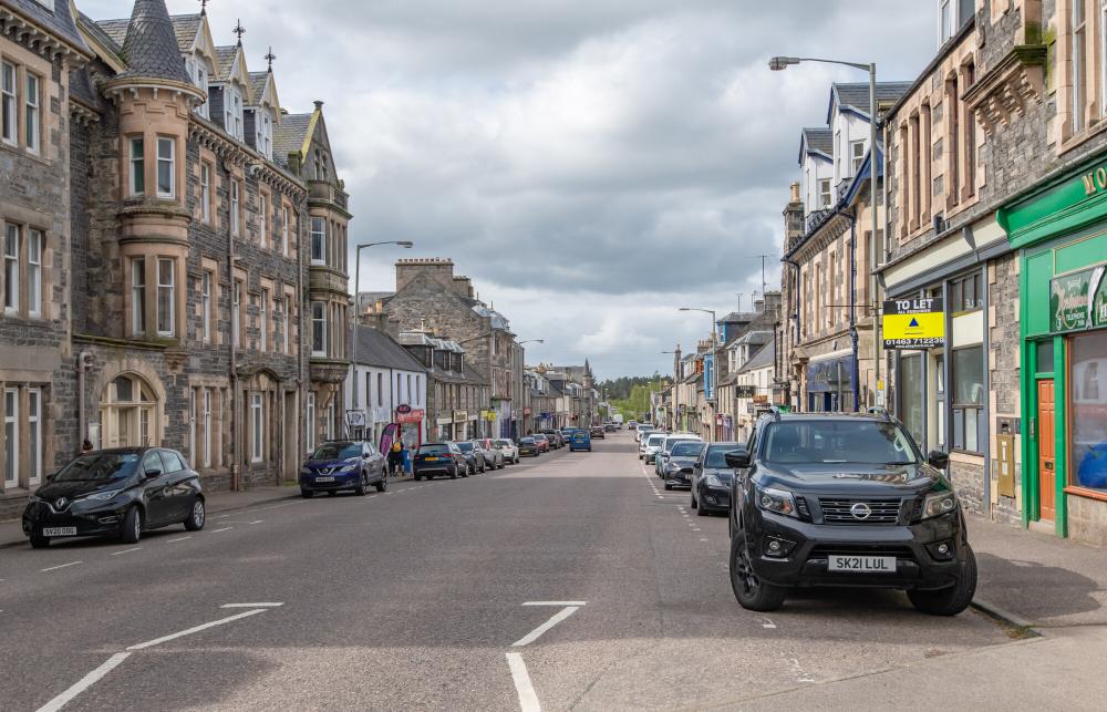 Grantown-on-Spey main street with cars parked on either side.