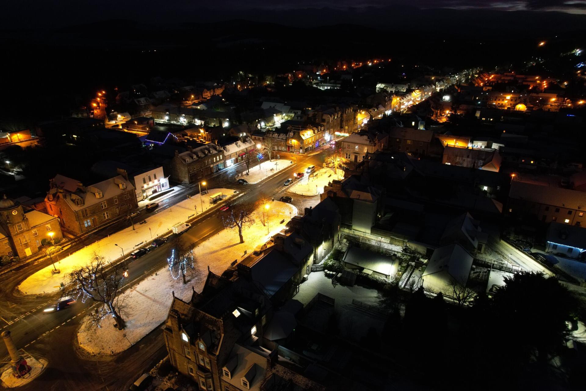 Aerial night view of Grantown-on-Spey main street with snow on the ground.