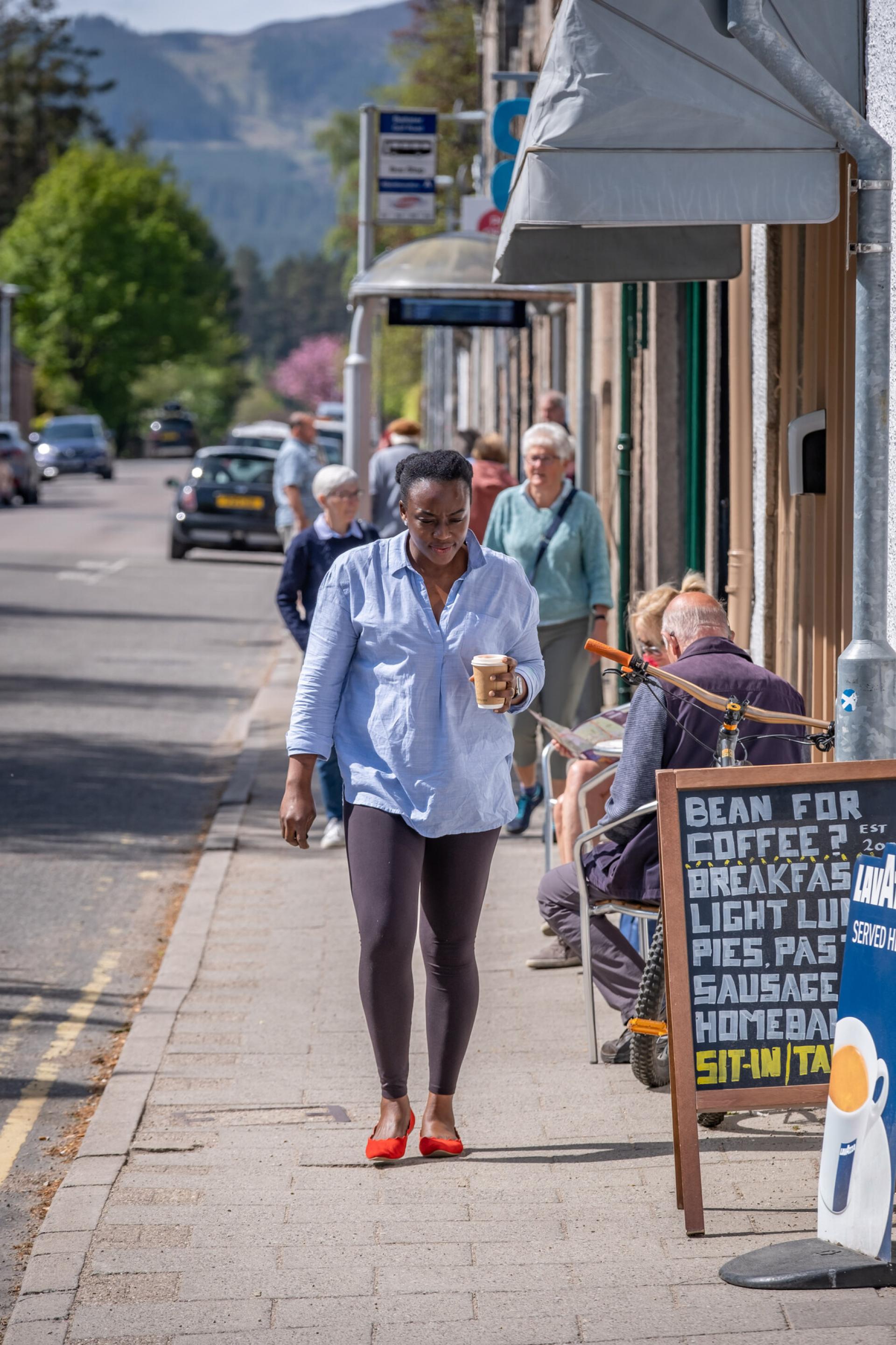 Woman enjoys a takeaway coffee in Ballater.