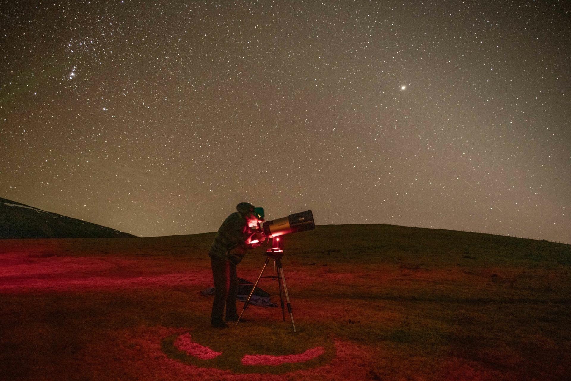 Studying the night sky through a telescope at the Tomintoul and Glenlivet Dark Sky Park in the Cairngorms National Park.