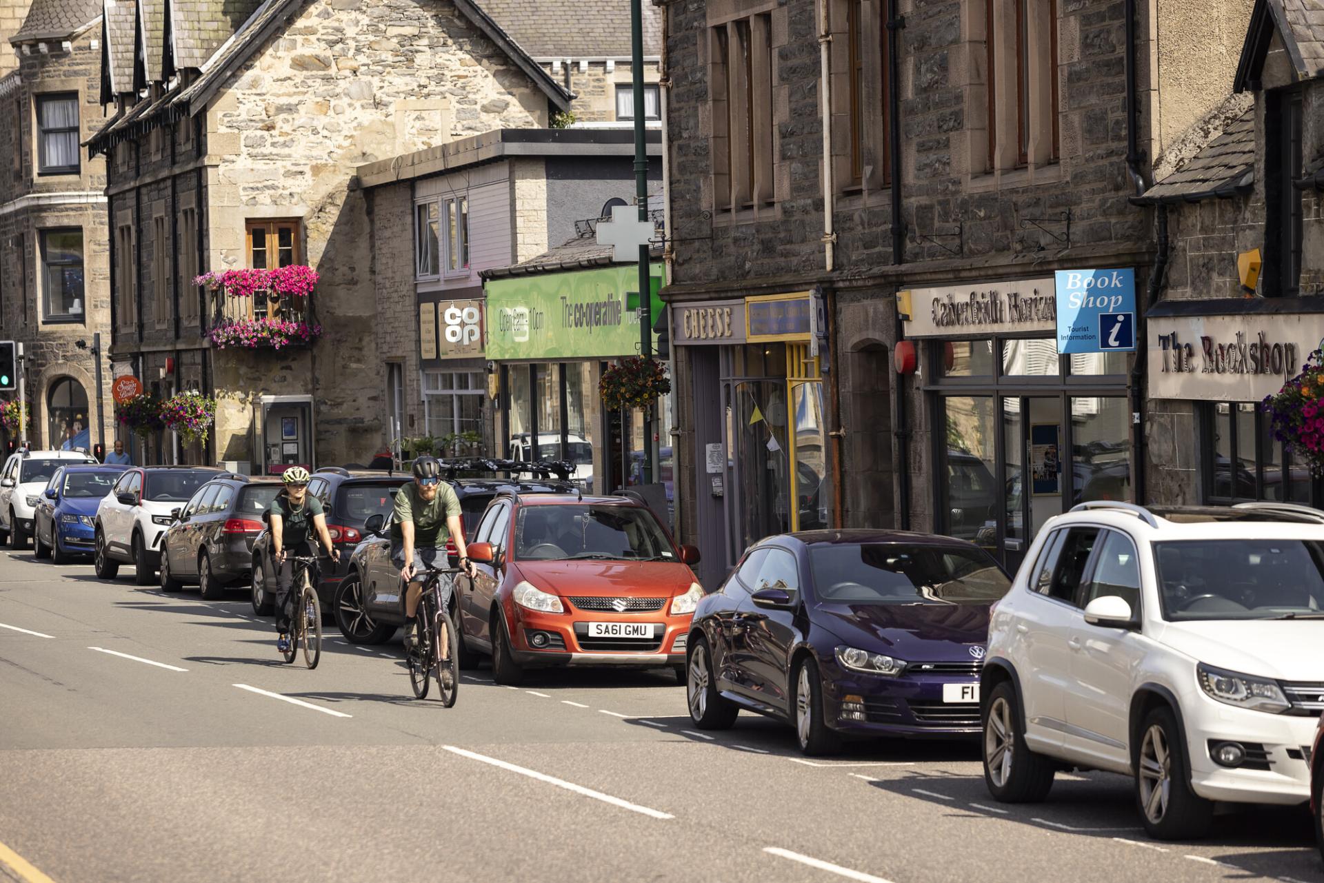 A street scene with two cyclists riding down the street.