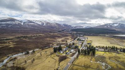Aerial view of Dalwhinnie with surrounding mountains with patches of snow.