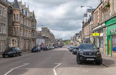 Grantown-on-Spey main street with cars parked on either side.