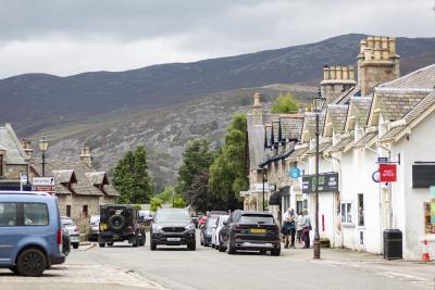 A streetscape with cars and shops and view to hills in the background.
