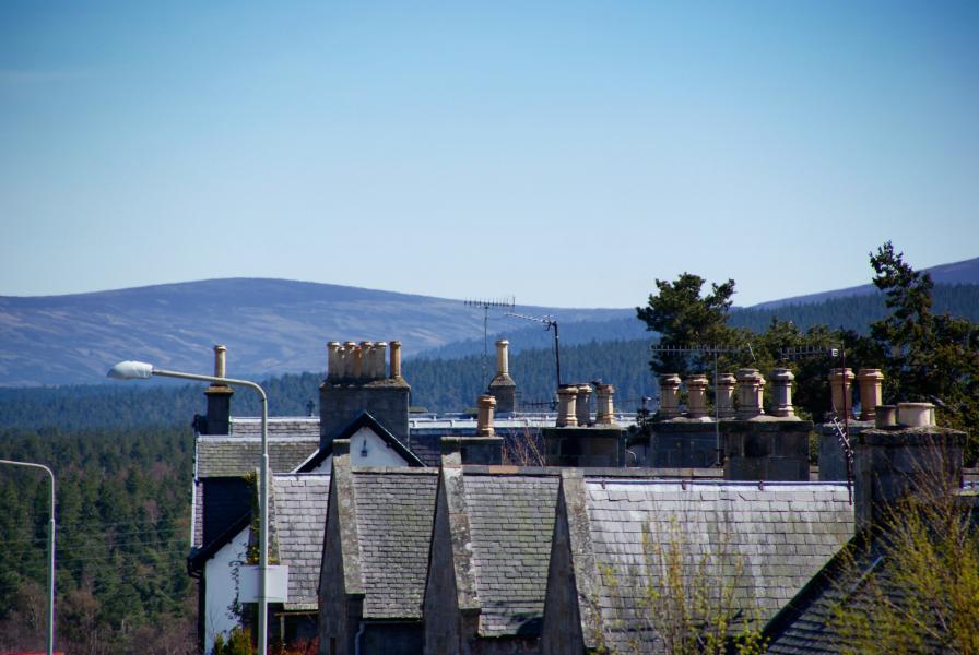 Roof tops with forests and mountains in the background and blue sky above.