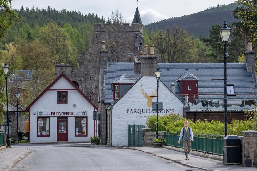Man dressed in tweed walking over a bridge in Braemar.