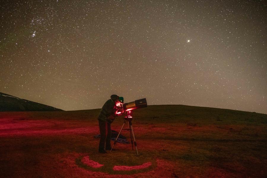 Studying the night sky through a telescope at the Tomintoul and Glenlivet Dark Sky Park in the Cairngorms National Park.