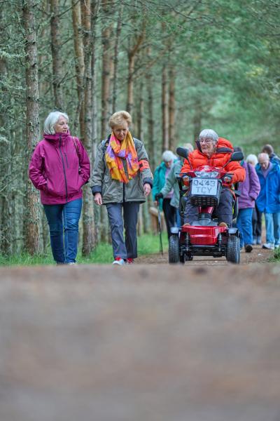 A group of people on the Boat of Garten health walk on forest path.