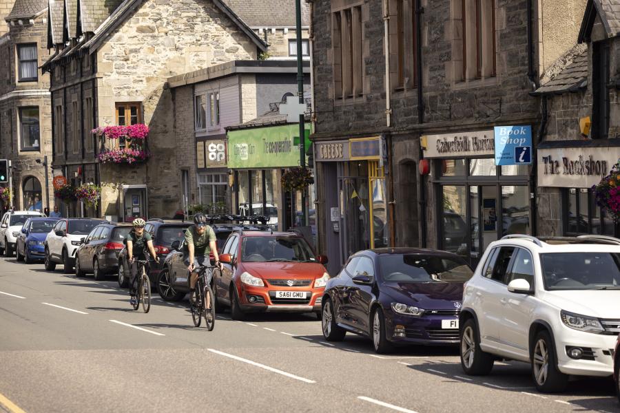 A street scene with two cyclists riding down the street.