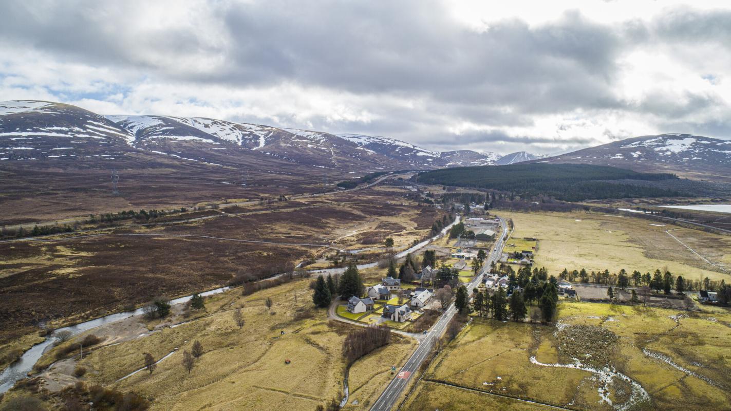 Aerial view of Dalwhinnie with surrounding mountains with patches of snow.