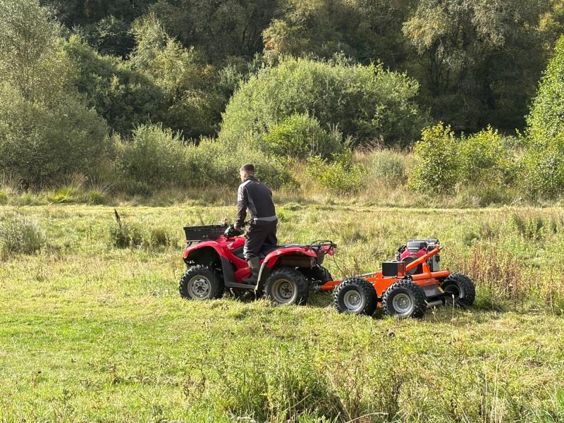 Man on a quad bike pulling a flail mower