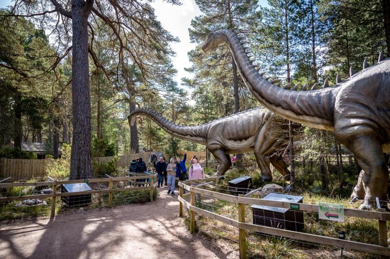 family walking walking past trees and models of dinosaurs
