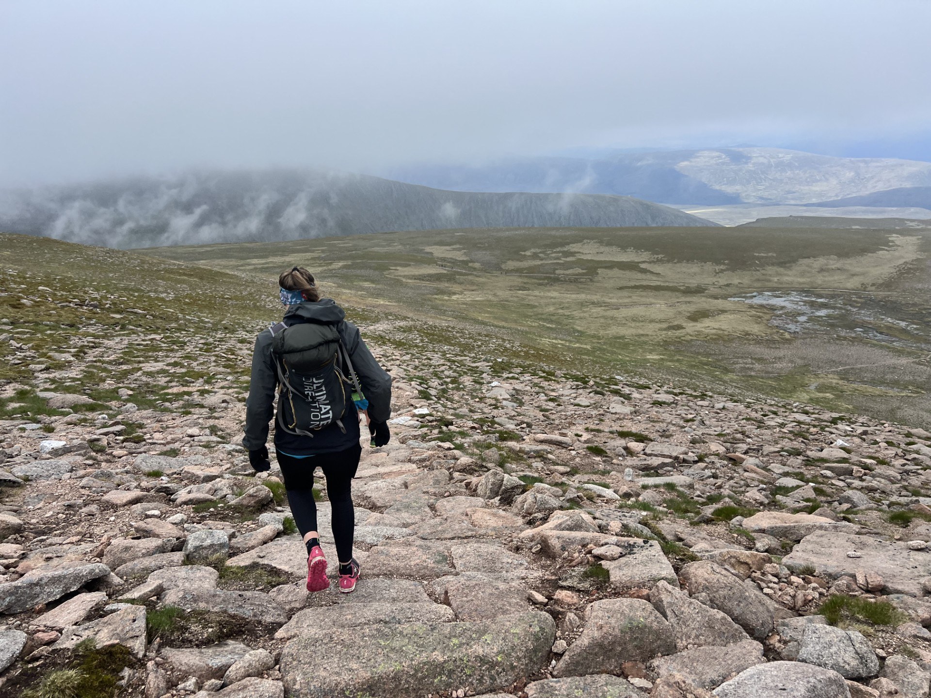 person with back to camera hillwlking with mountains in the background