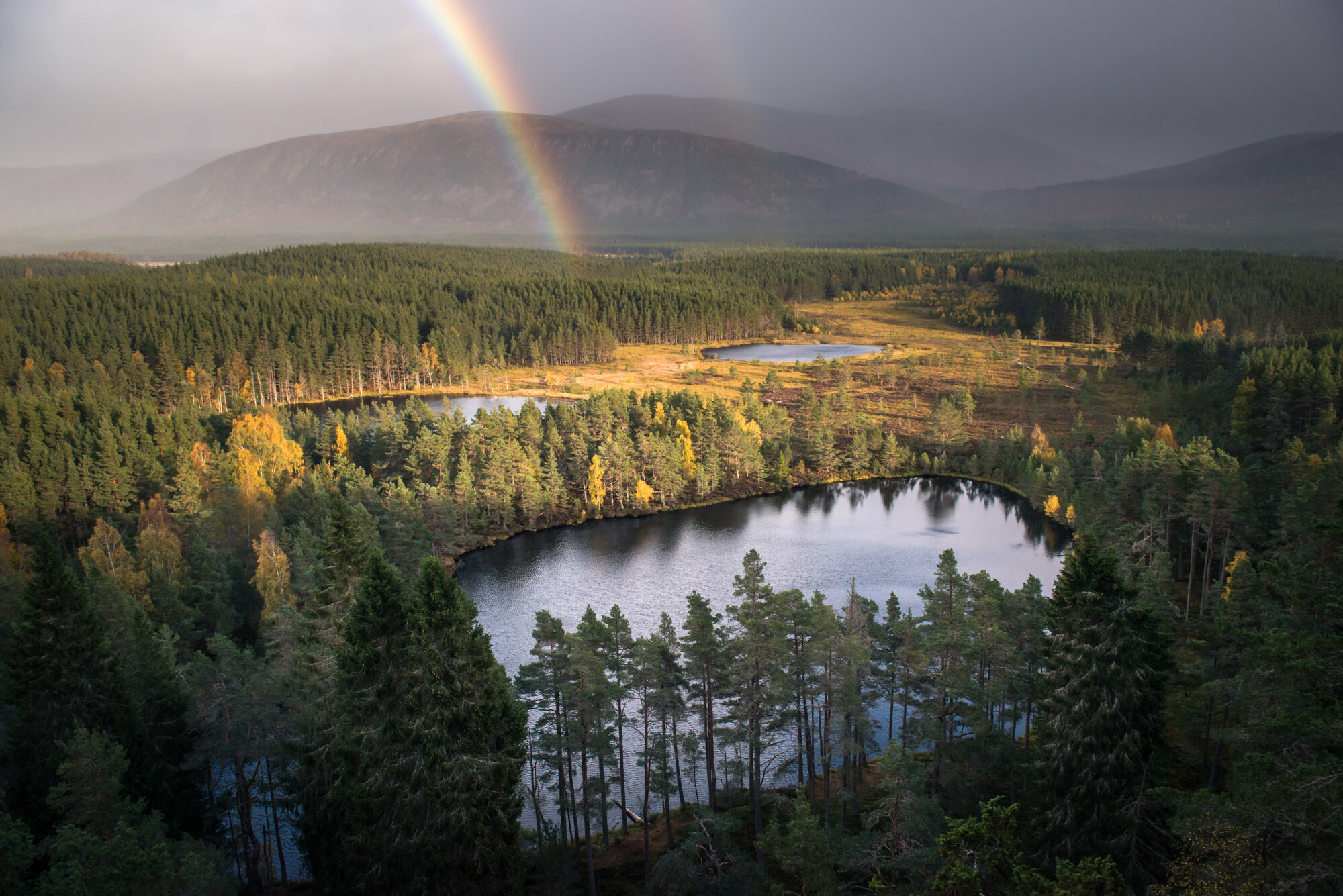 Looking down on Uath Lochans from Farleitter Crag with a rainbow in the distance.