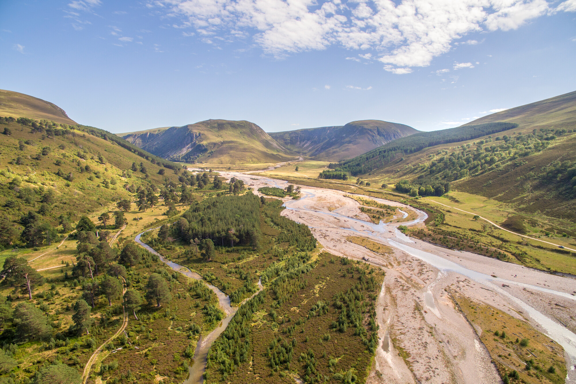 Aerial view of river flowing through Glenfeshie with surrounding trees and mountains