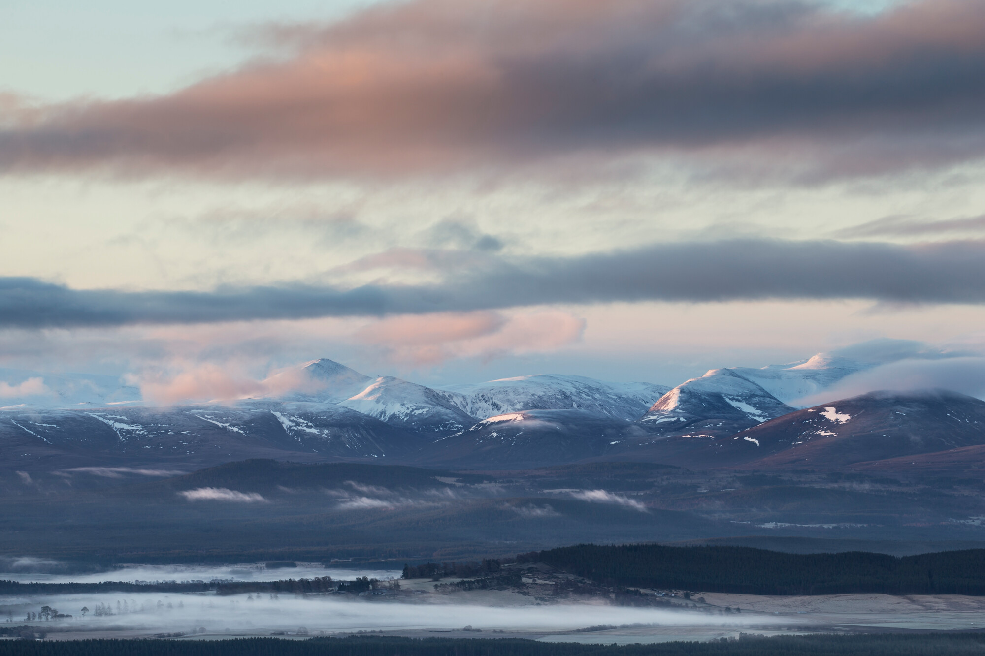 A view towards the snow-capped Cairngorms mountains at dawn