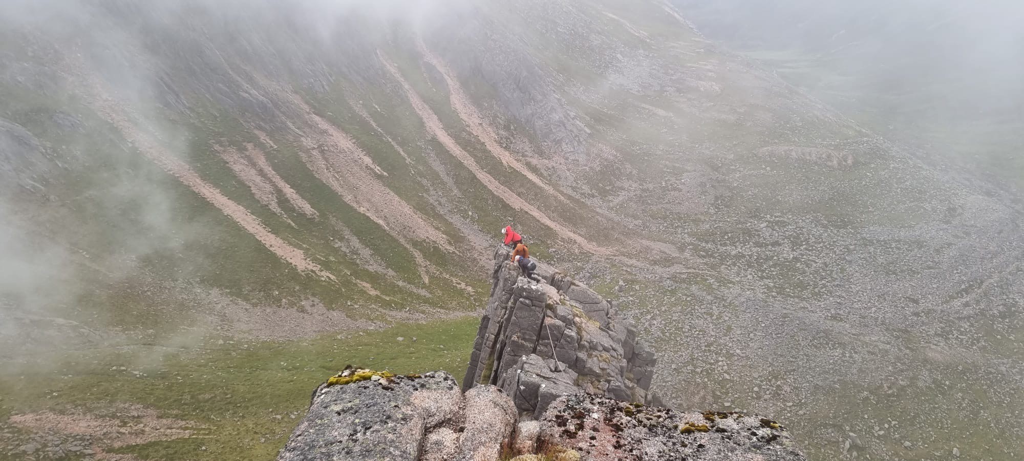 Three mountain rescue volunteers on the cliff top preparing to rescue climbers