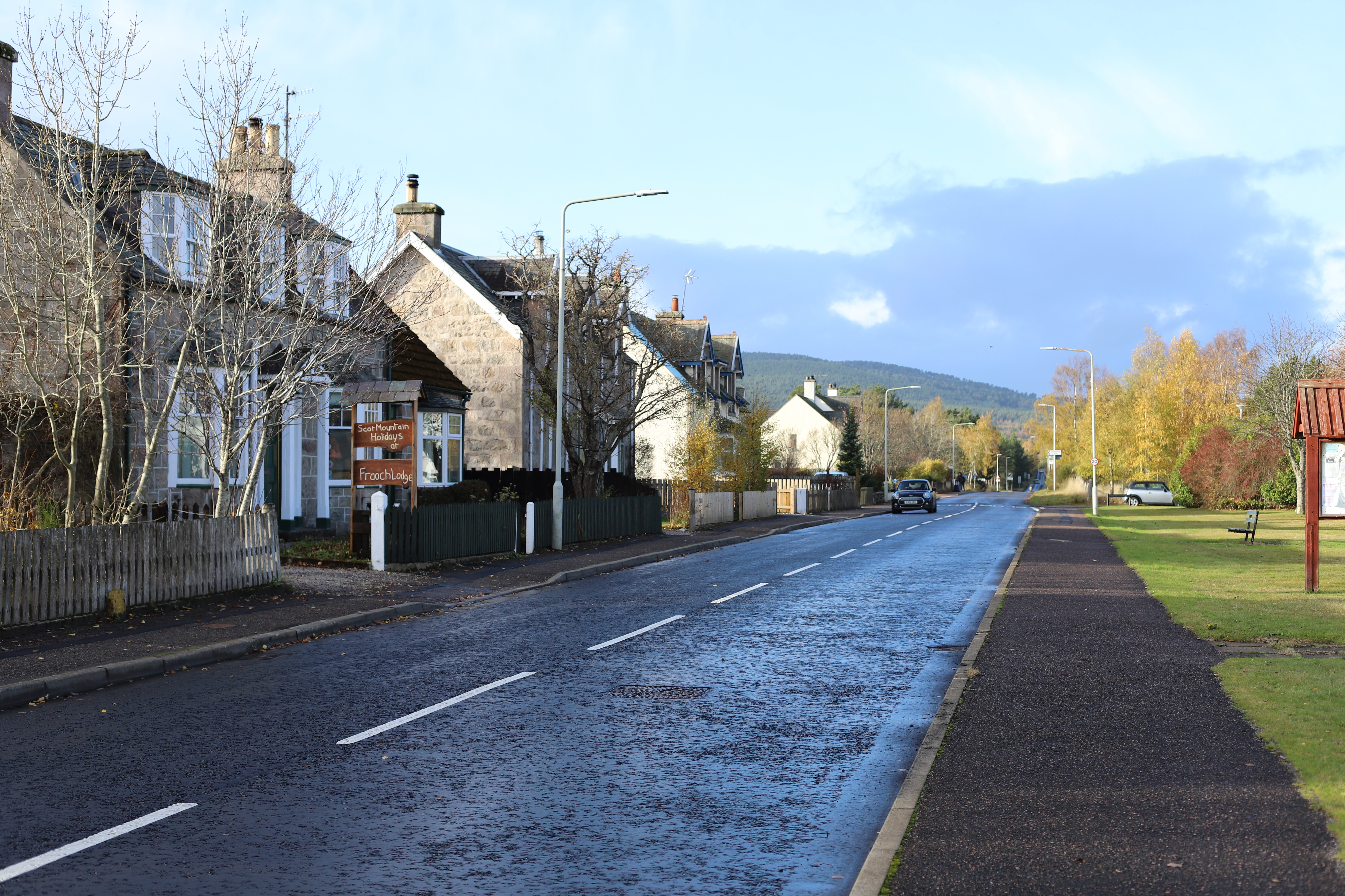 An image of a street with a cloudy sky and two parked cars.