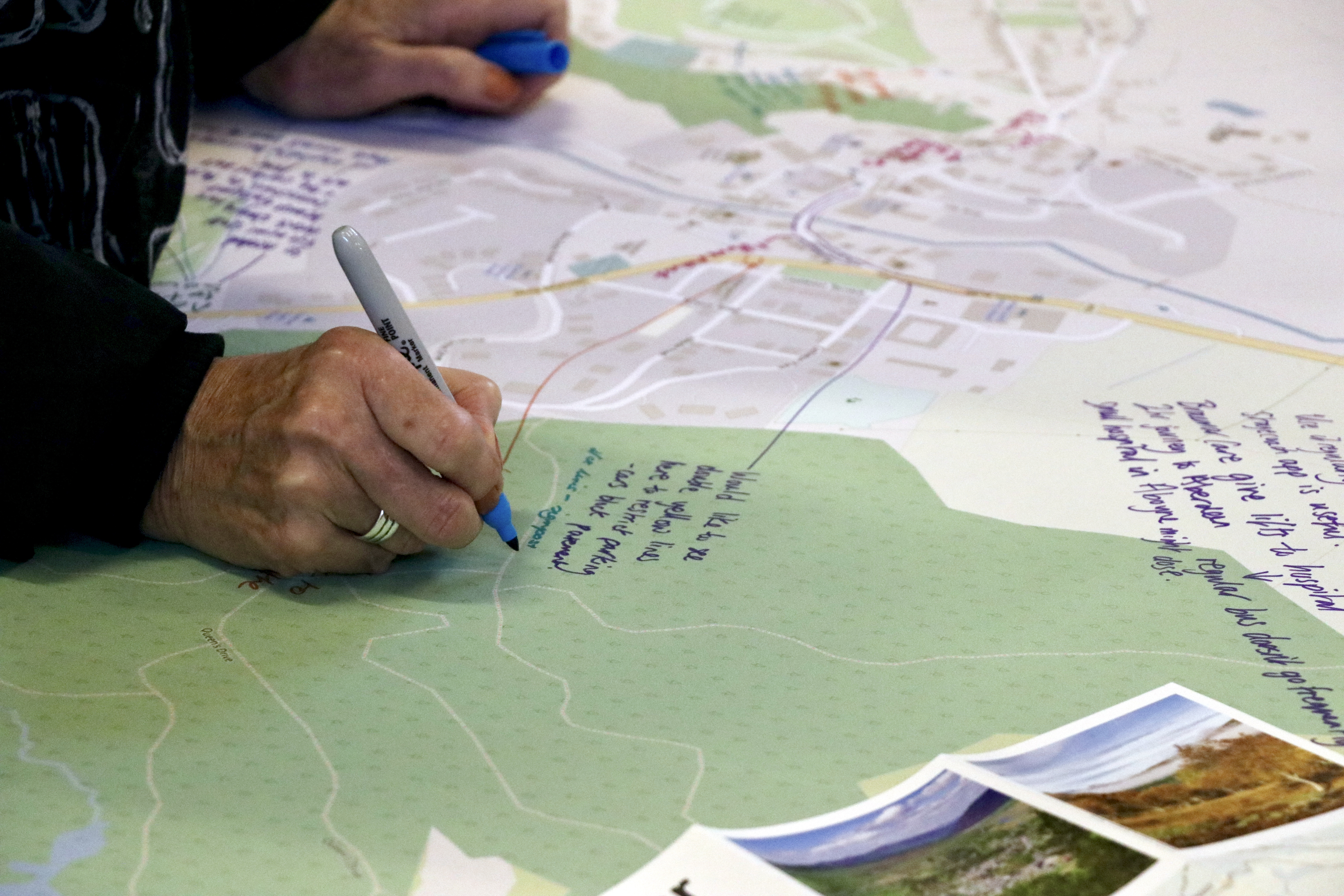 A hand holding a pen writing on a large map