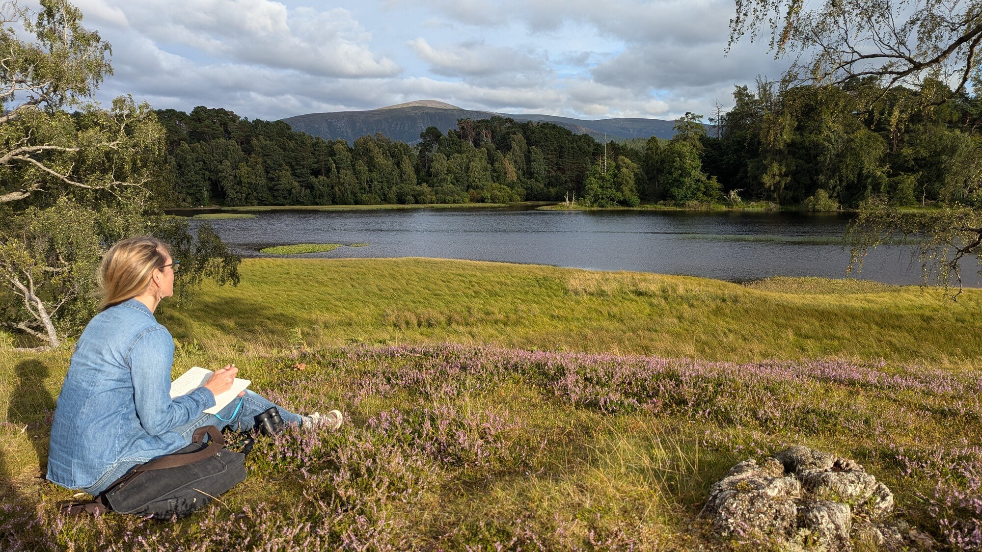 Female writing in note book, over looking Loch Insh