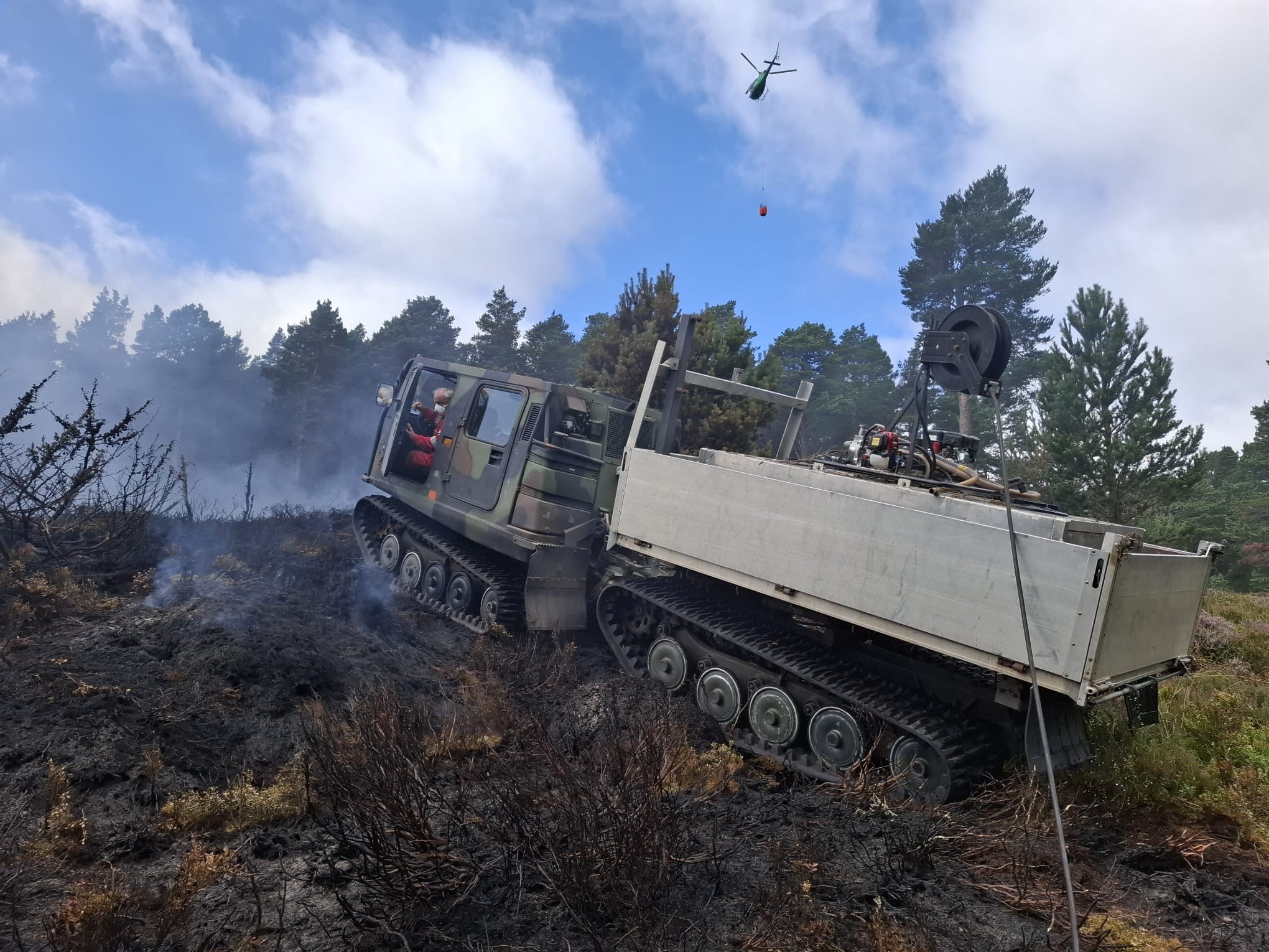 Image of helicopter in the sky, with an ATV vehicle in the foreground.