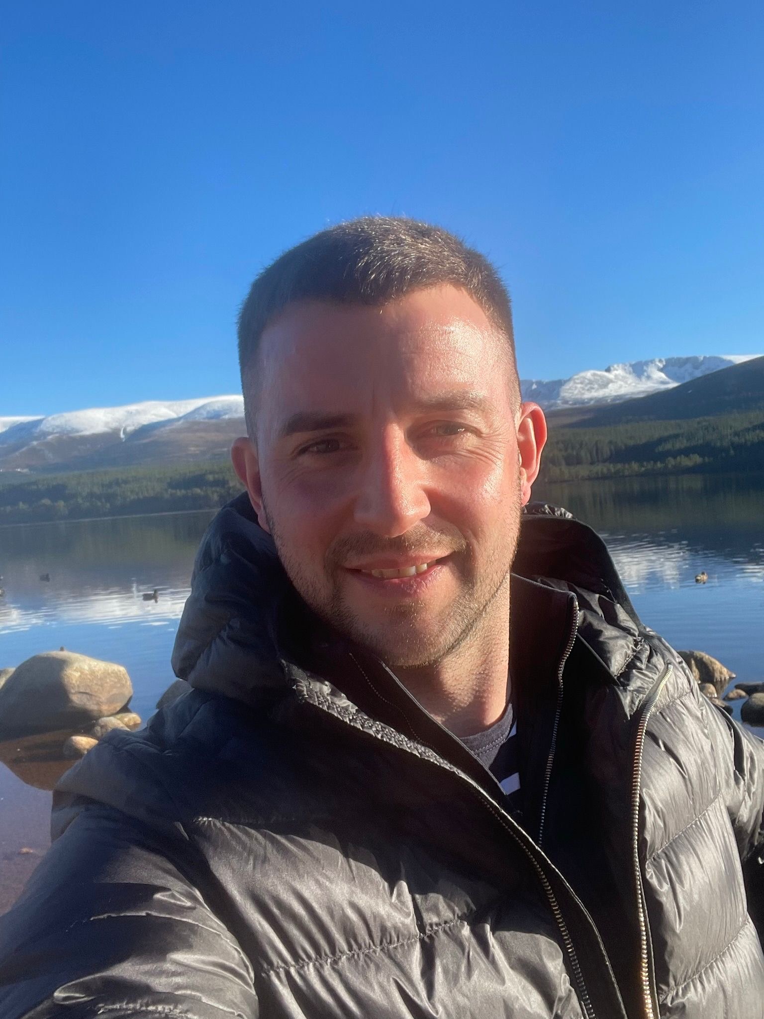 Image of Sean Williamson wearing a black jacket in front of a loch.