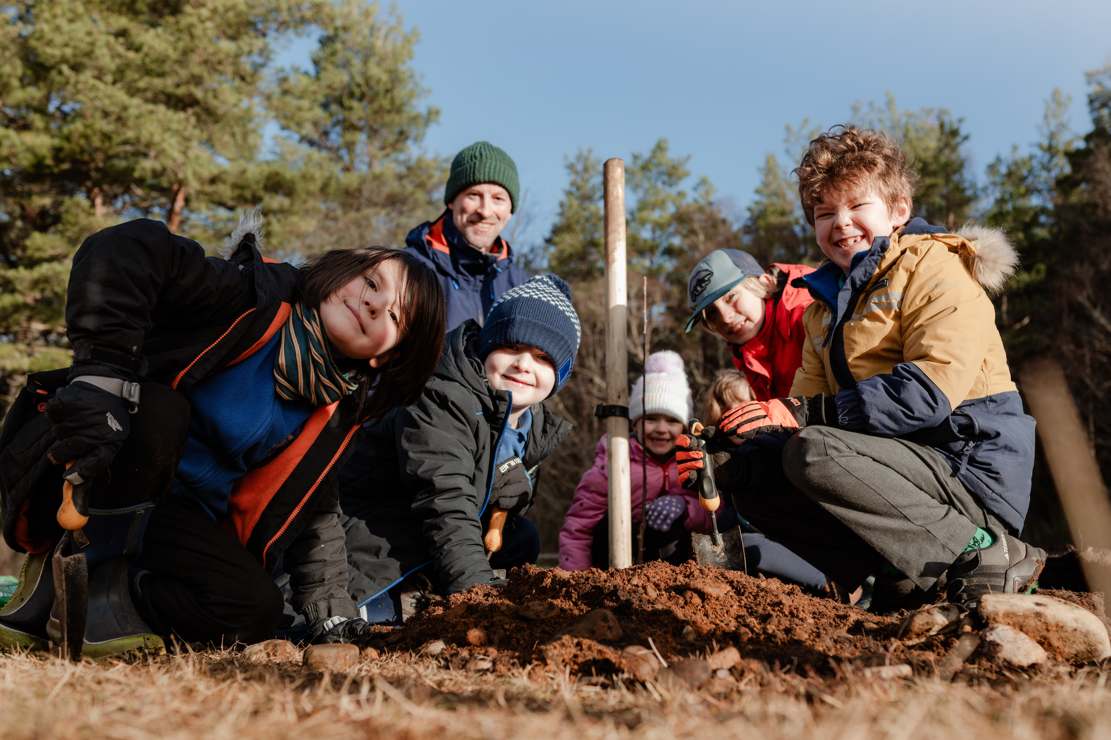 Group of five children in the foregrounf gardening and one adult in the background
