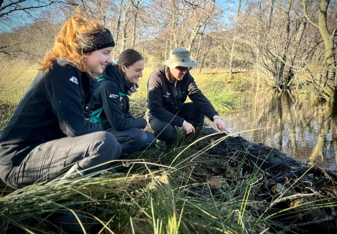 Beaver project manager Jonathan and beaver rangers Emily and Rhona looking at signs of beaver activity at the waters edge.