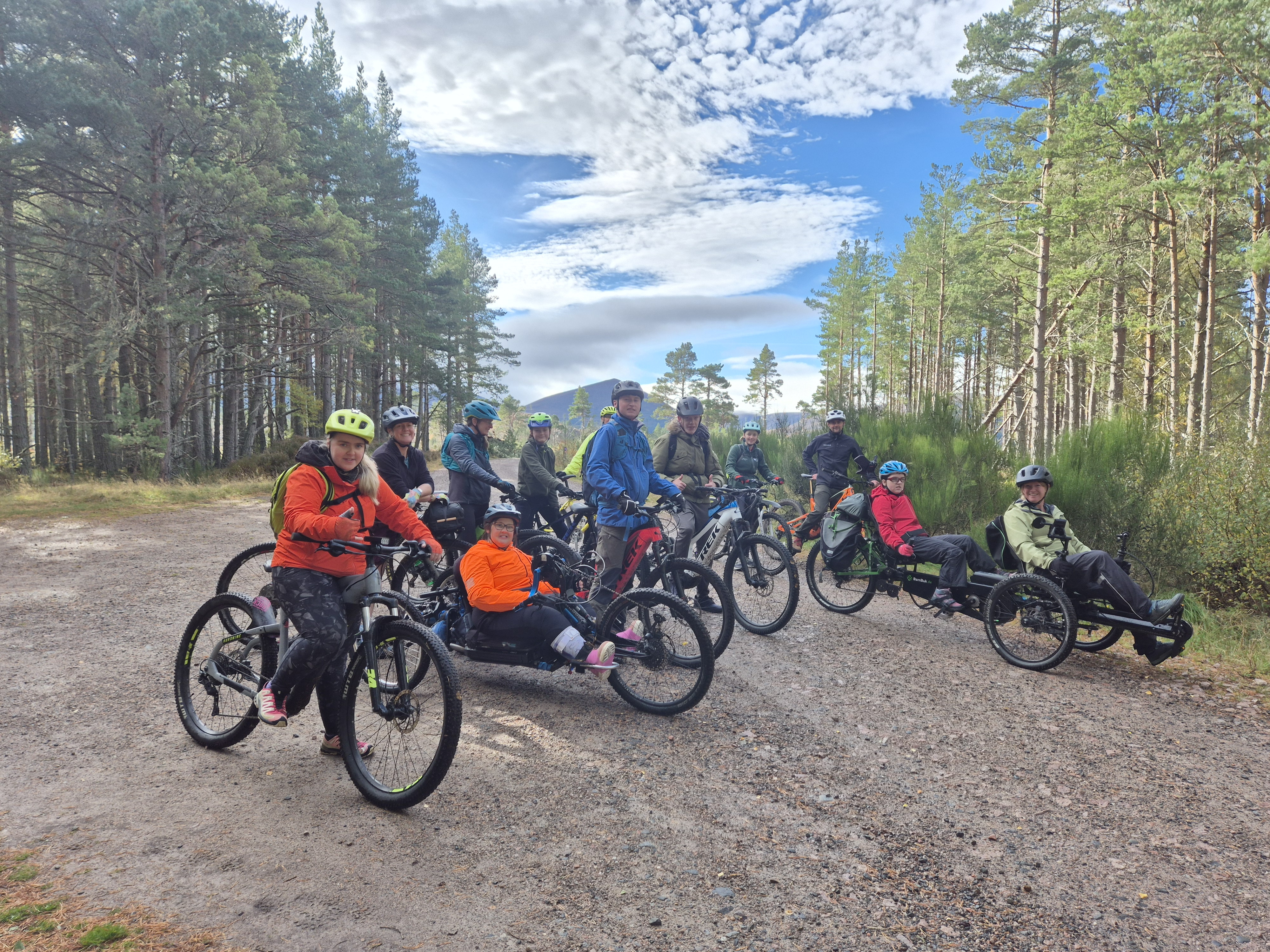 group of young peopel on bikes and adapted bikes on a woodland trail