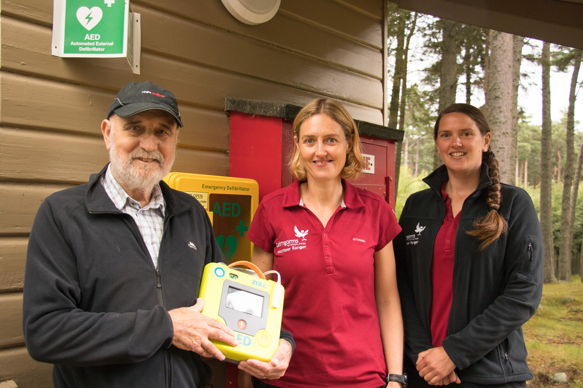 Man holding a Defibrillator with two park rangers.