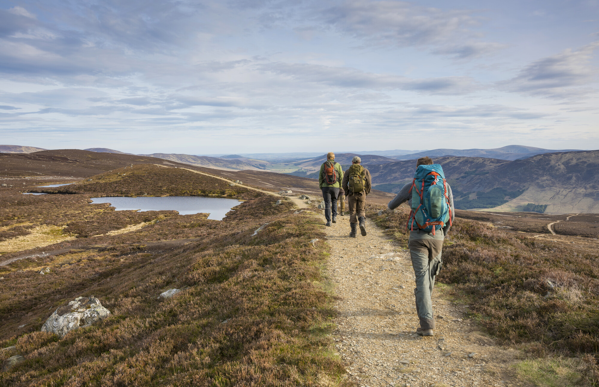 Four people with backpacks, hill walking near Loch Brandy in Glen Clova
