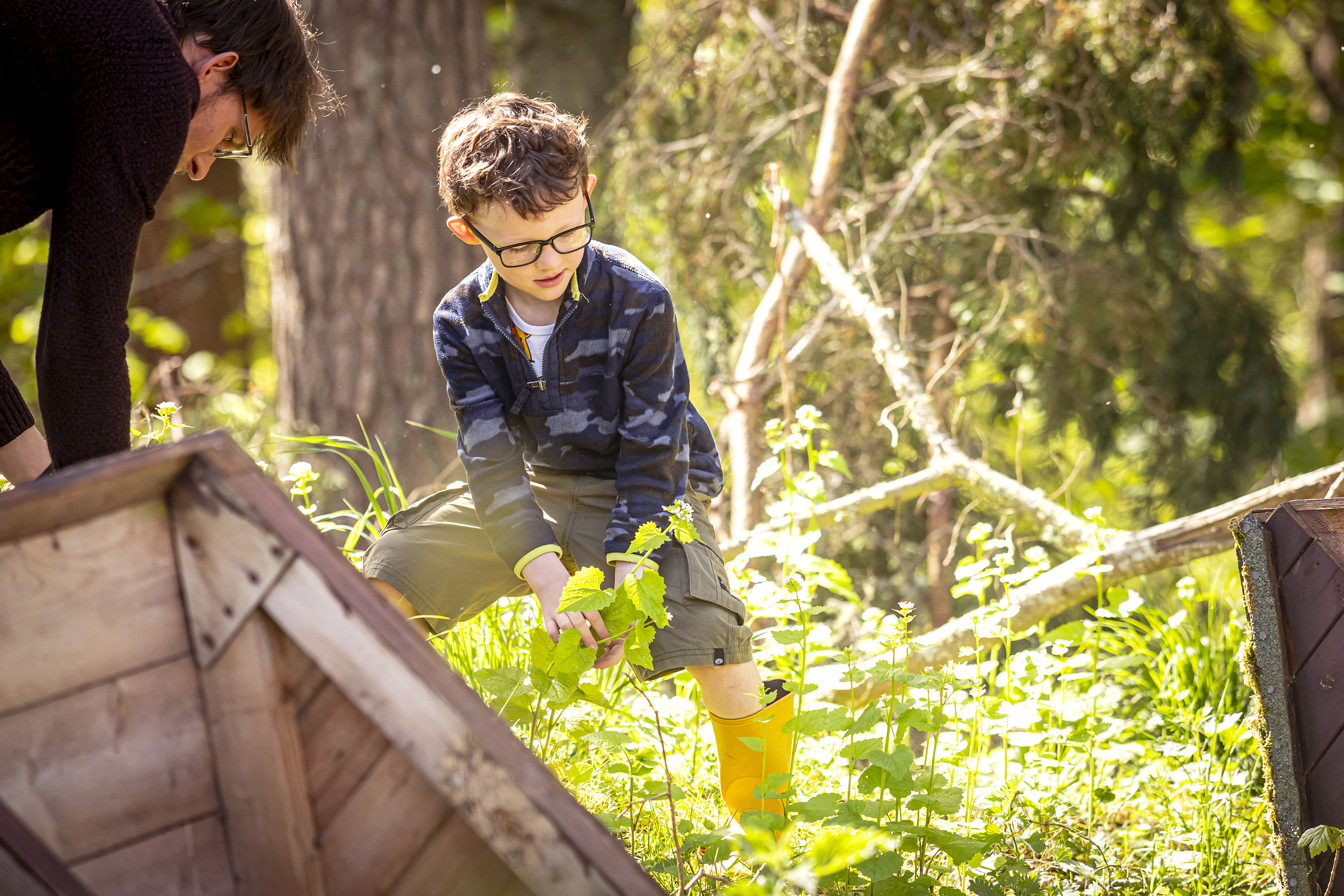 A child wearing wellies helping an adult outdoors in nature