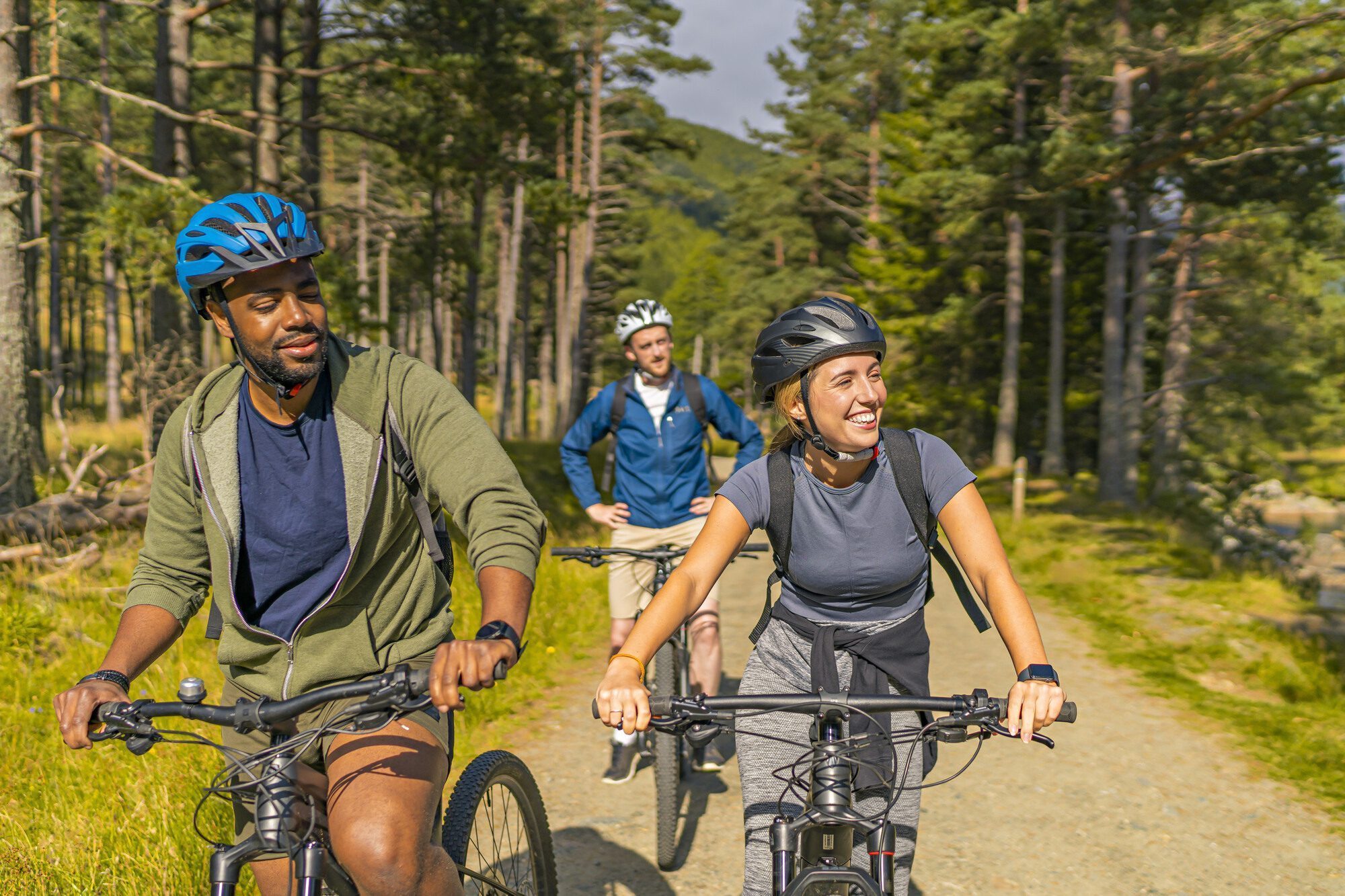 Three cyclists stopped on woodland path.