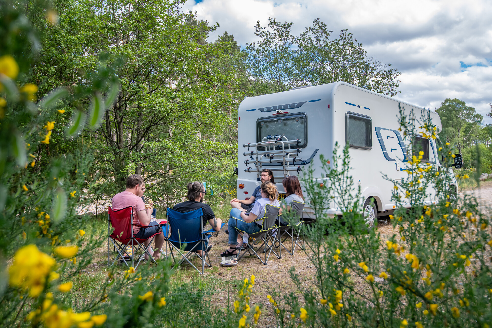 People sat on camping chairs next to a campervan in the National Park