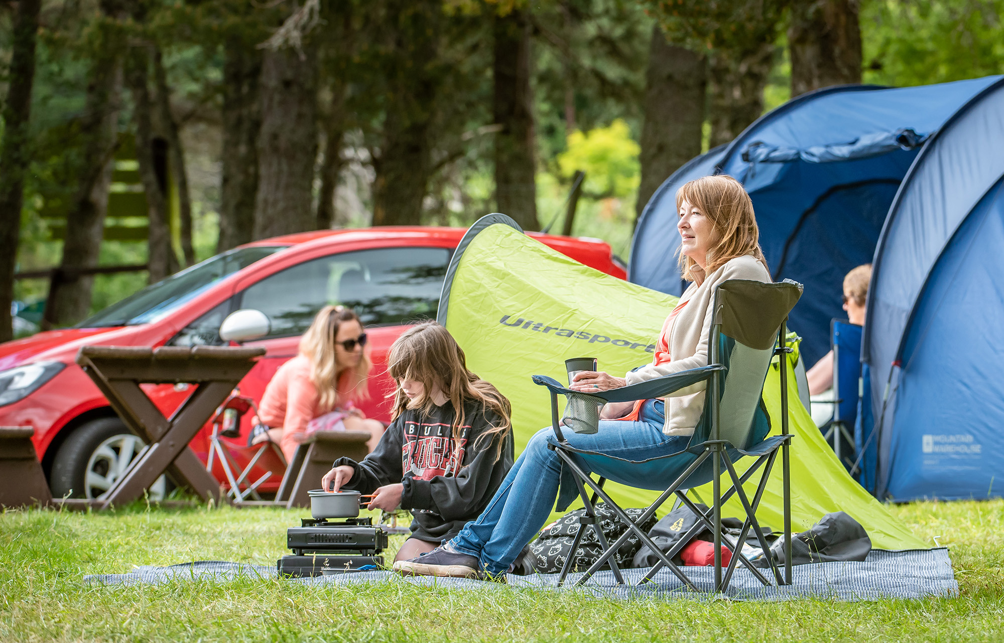Family using gas camping stove at Loch Morlich campsite.