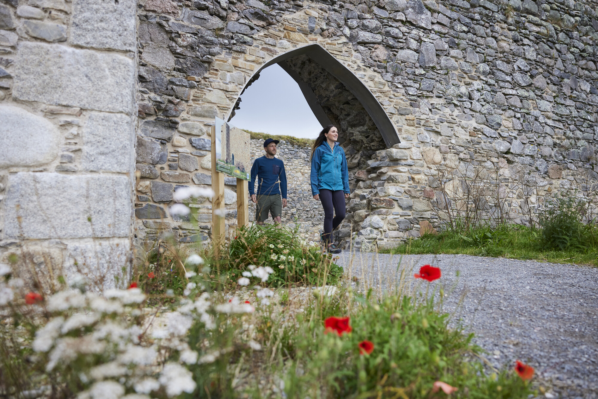 Two people walking through an archway in Castle Roy in the Cairngorms National Park.