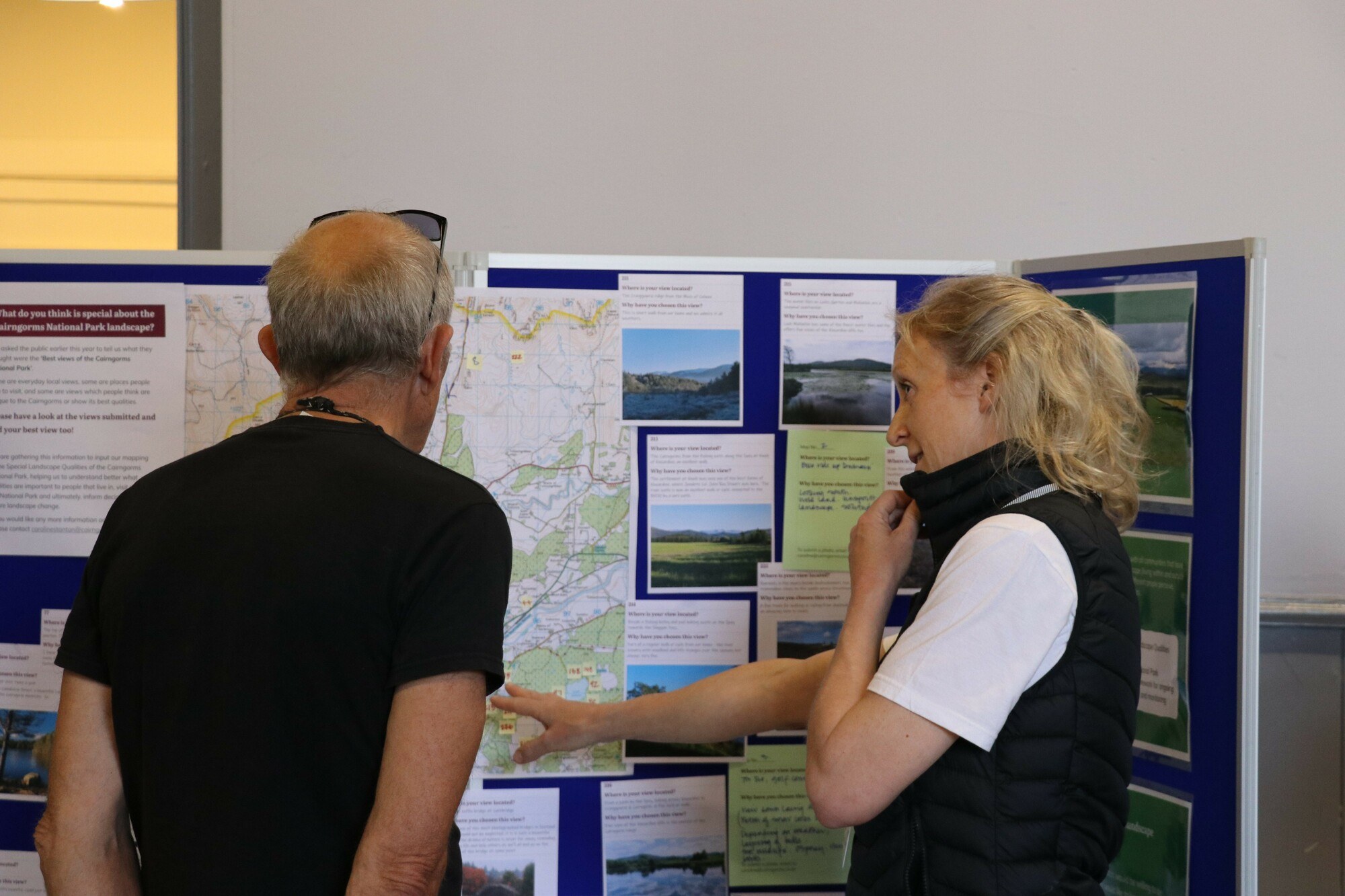 Two people looking at an information board at a C2030 drop-in event in Carrbridge.